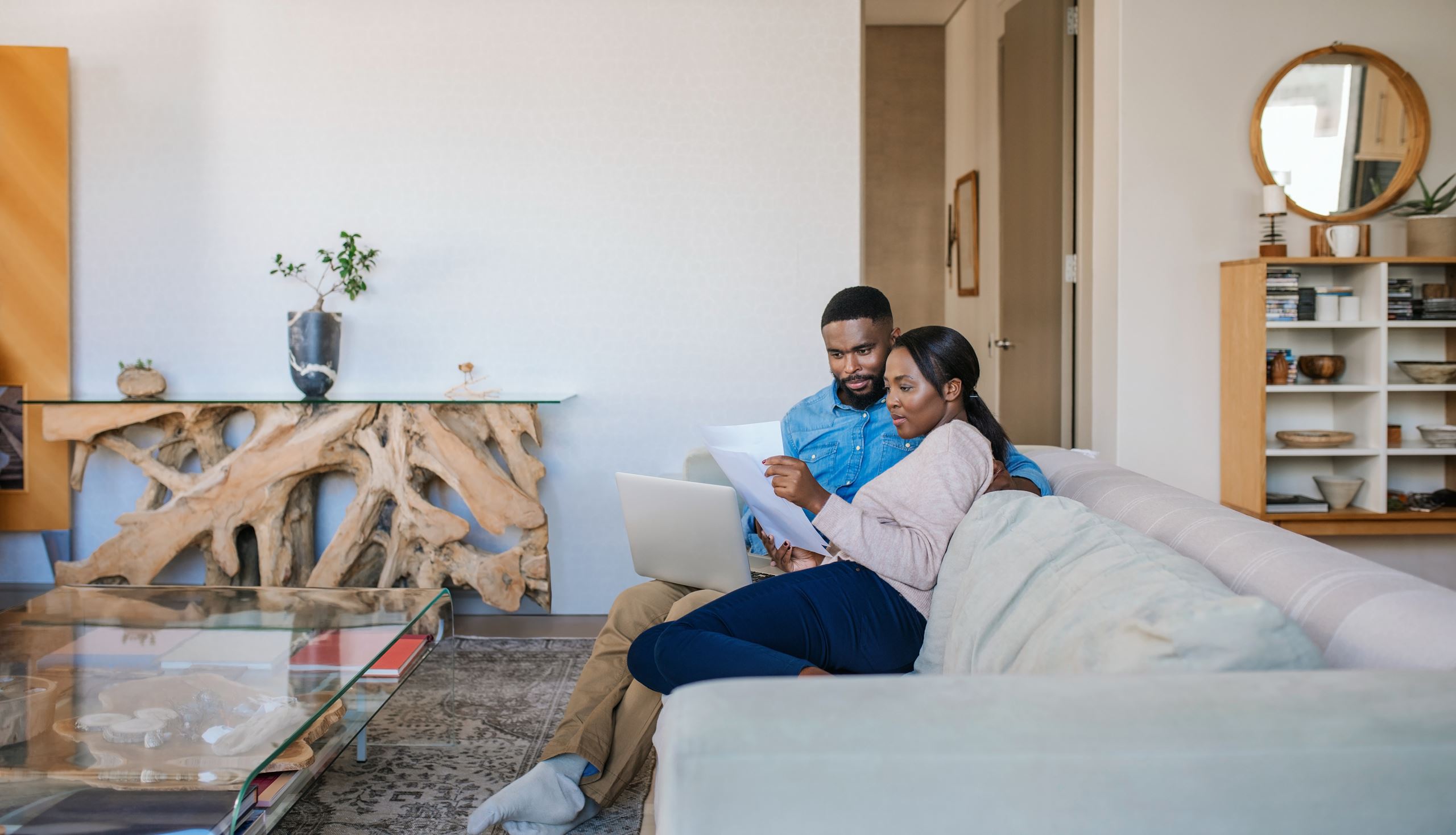 Couple sitting on couch using online banking services on laptop