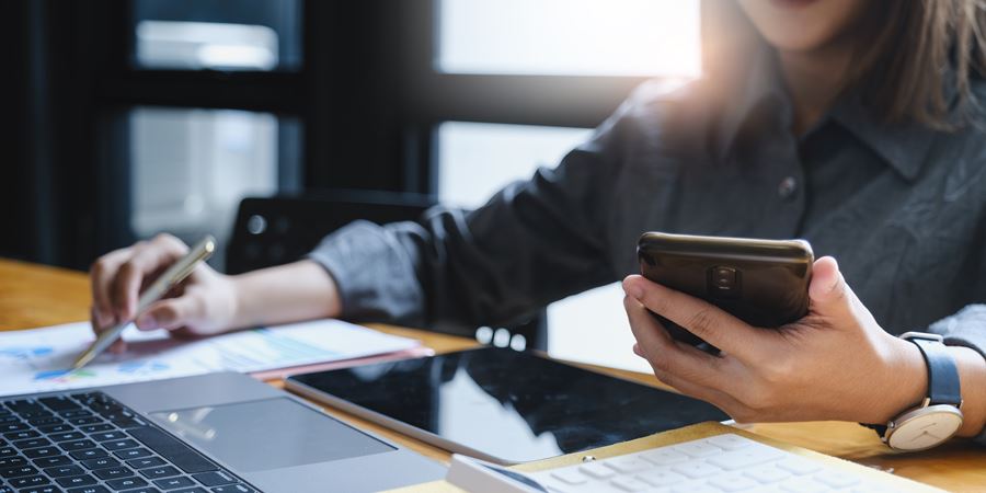 woman on her phone while using computer