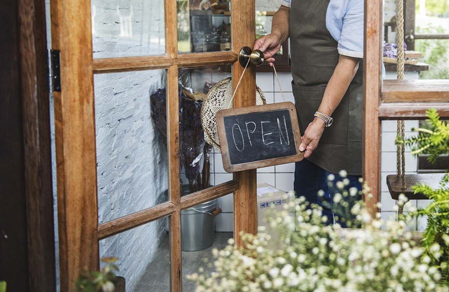Business owner flipping open sign on front door of business