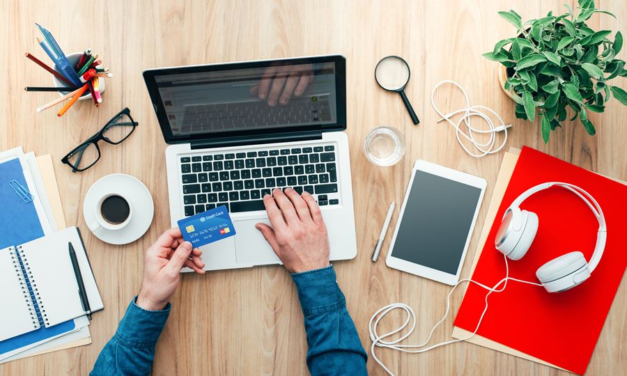 Man using computer laptop while holding credit card