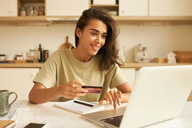 Woman using computer while holding credit card