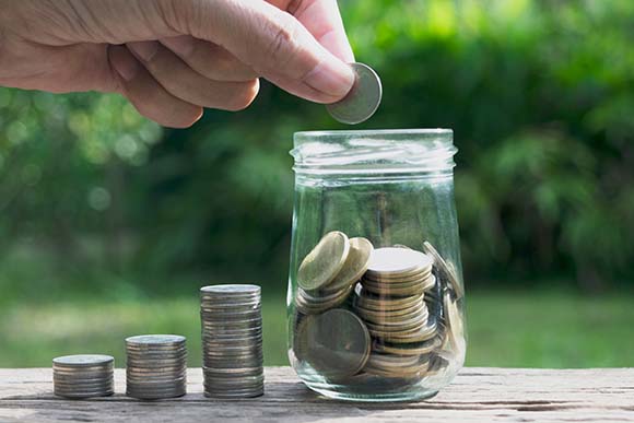 Man putting coins in a jar at the end of a coin chart