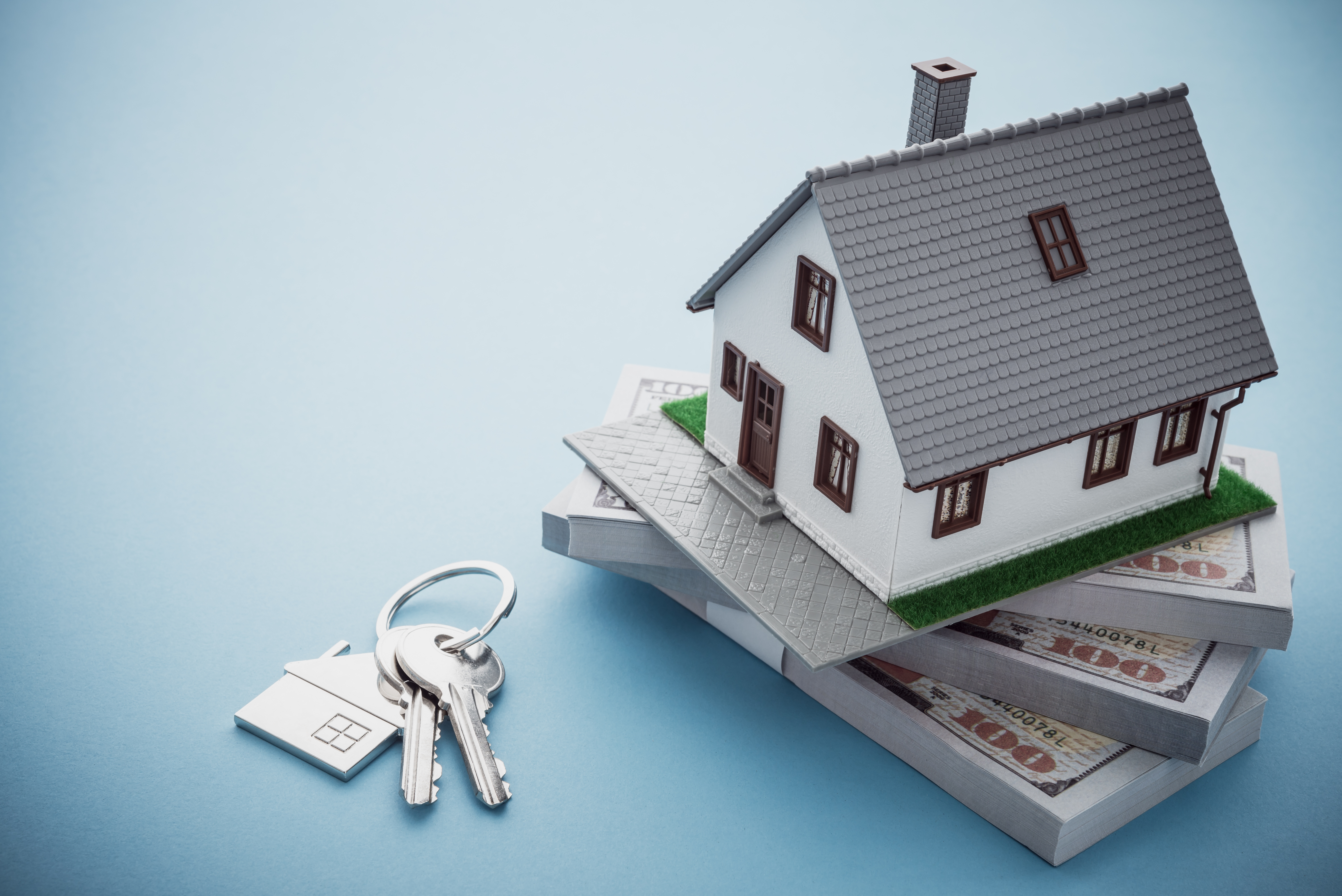 Nice house model laying on a stack of money